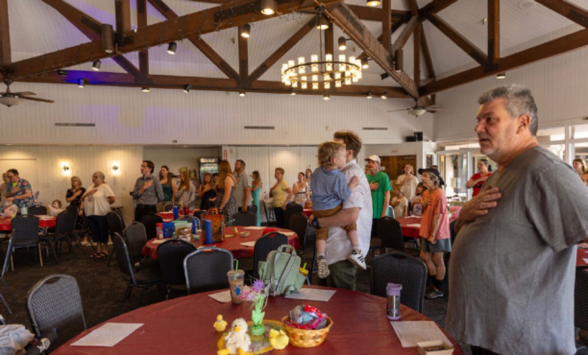 Families standing for the Pledge of Allegiance before lunch at the Easter Egg Hunt