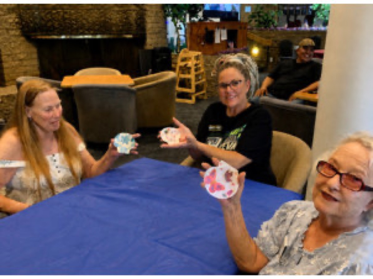 Members at a table displaying their painted seashell creations